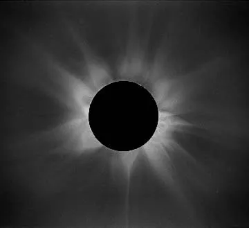 Bright tendrils of light extend out around the border of the black disk of the Moon during a solar eclipse.